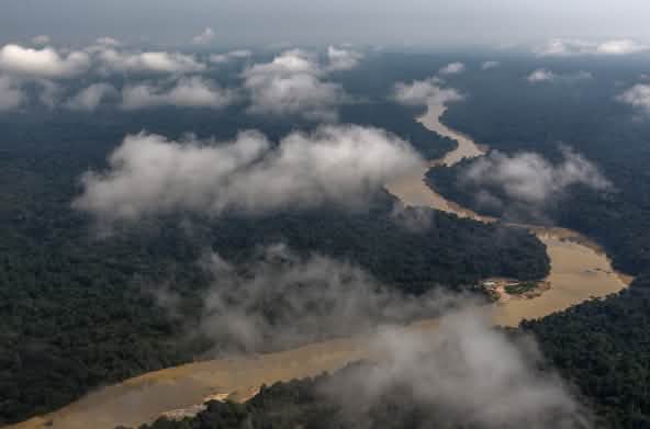 Vista aérea con nubes de un río serpenteando por la selva tropical amazónica