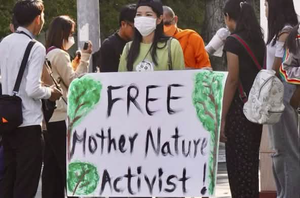 Joven mujer con un gran cartel en el que se lee «¡Liberad a los activistas de Mother Nature!».