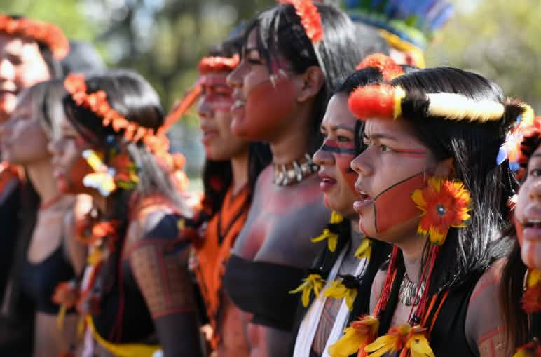 Mujeres indígenas durante una protesta en Brasil Ocho mujeres indígenas, con adornos de plumas en la cabeza, pendientes de plumas amarillas y rojas, y la cara pintada de rojo y negro