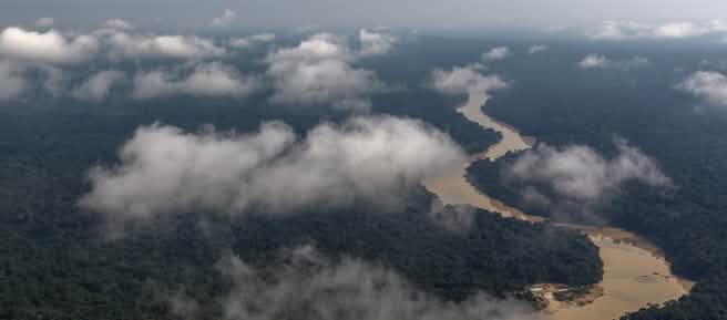 Vista aérea con nubes de un río serpenteando por la selva tropical amazónica