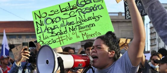 Mujer con megáfono durante las protestas en contra de la minería en Panamá, en 2023. Al fondo, una pancarta "El Agua, el Aire, la Naturaleza y la Salud, no tienen precio"