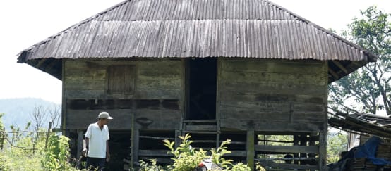 Una persona delante de una antigua casa de madera