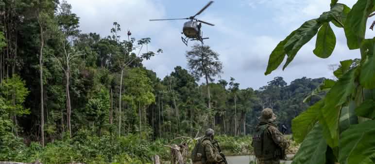 Operación de la agencia medioambiental IBAMA contra la minería ilegal de oro en la selva tropical Dos agentes armados de la agencia ambiental IBAMA, vestidos con trajes de camuflaje, bajo un helicóptero durante en una operación de contra la minería ilegal de oro en la selva tropical amazónica