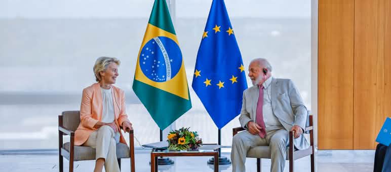 Me quiere, no me quiere: ¿llegarán a un acuerdo para facilitar acceso a Europa de las materias primas de Brasil y otros países de Mercosur y América Latina? Presidente de Brasil, Lula da Silva y presidenta de la Comisión Europea, Ursula von der Leyen sentados, mirándose, delante de dos banderas, una de Brasil y la otra de la Unión Europea
