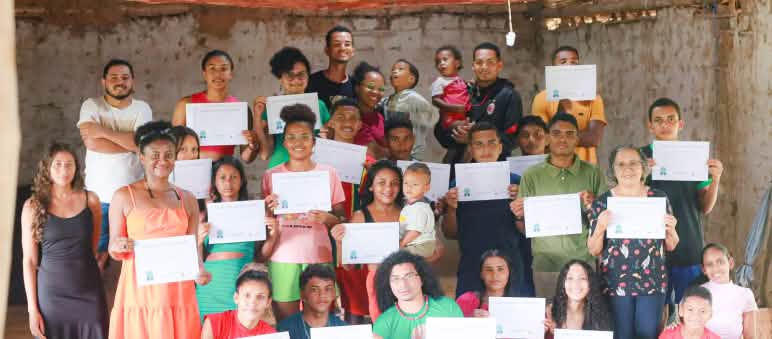 Jóvenes de territorios afectados por la expansión del agronegocio en el estado brasileño de Maranhão se gradúan en un curso de comunicación popular 31 personas jóvenes y niños, de pie y cuclillas, en una sala sosteniendo los diplomas obtenidos tras haber completado un taller de comunicación
