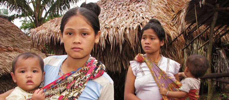 Las indígenas Pala'wan necesitan el territorio Dos mujeres con sus bebés frente a las casas de su comunidad