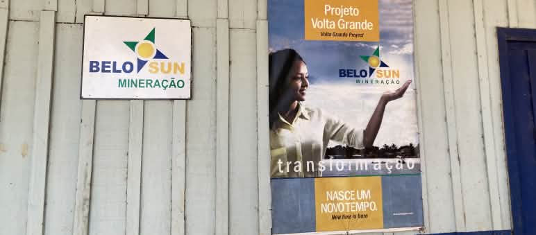 Anuncio de la empresa minera Belo Sun en el pueblo de Ressaca Un cartel de la empresa minera Belo Sun y un cartel publicitario de la empresa en la pared de una cabaña de madera