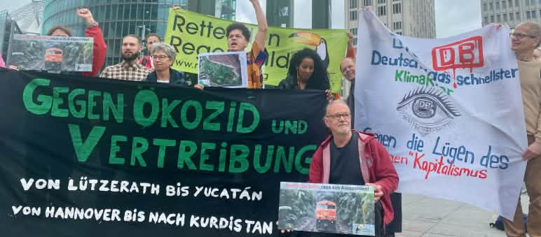 Manifestación en Potsdamer Platz, Berlín, frente a la sede de DB, mayo 2024 Un grupo de personas protesta con grandes pancartas de varias organizaciones, delante de unos edificios