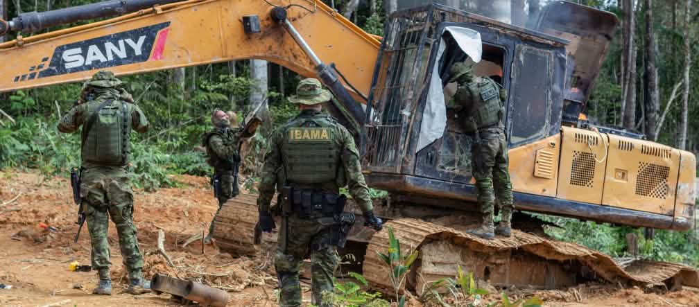 Policías armados de la agencia ambiental IBAMA intervienen una draga utilizada para la extracción ilegal de oro en la selva del pueblo indígena Munduruku. Intervención de la agencia medioambiental IBAMA. Un grupo de hombres con trajes militares intervienen una draga amarilla en la selva tropical