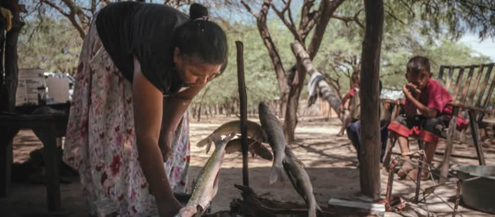 La cultura de los Mataguayo se basa en la pesca del río Mujer asando pescado bajo la atenta mirada de dos niños