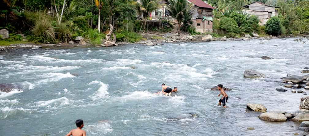 Niños disfrutando de un baño en el río Meureubo Niños bañándose y jugando en el río