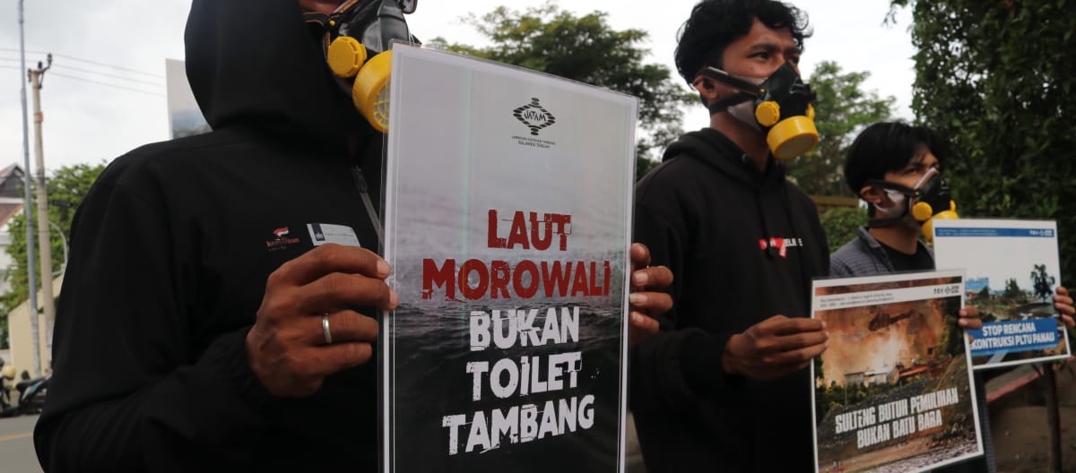 Tres activistas de Jatam con pancartas de protesta en las que se lee en indonesio "El mar de Morowali no es un retrete para la minería"