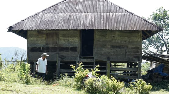 Una persona delante de una antigua casa de madera