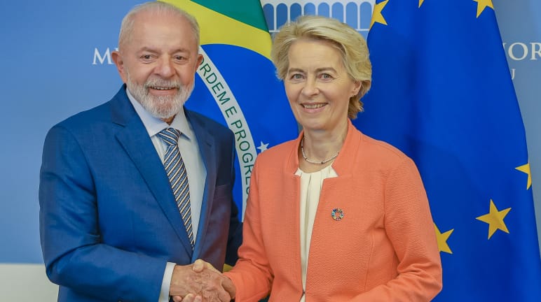 La presidenta de la Comisión Europea Ursula von der Leyen estrecha la mano del presidente de Brasil, Lula da Silva, delante de las banderas de Brasil y de la Unión Europea