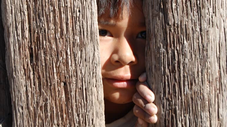 Tímida mirada de un niño entre dos maderos