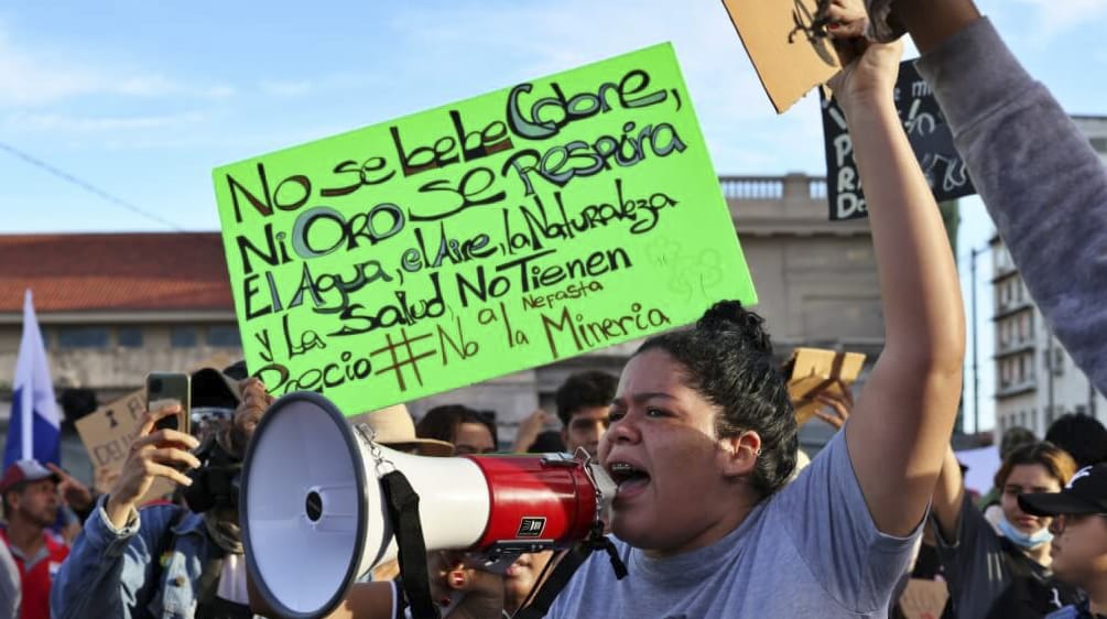 Mujer con megáfono durante las protestas en contra de la minería en Panamá, en 2023. Al fondo, una pancarta "El Agua, el Aire, la Naturaleza y la Salud, no tienen precio"