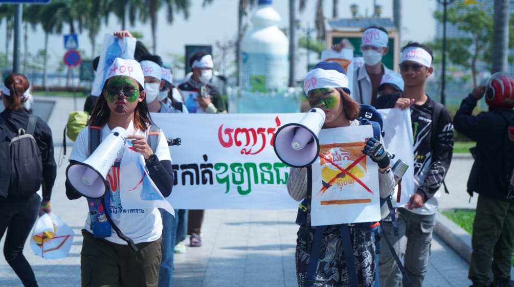 Un grupo de jóvenes estudiantes caminan por una calle portando megáfonos y pancartas