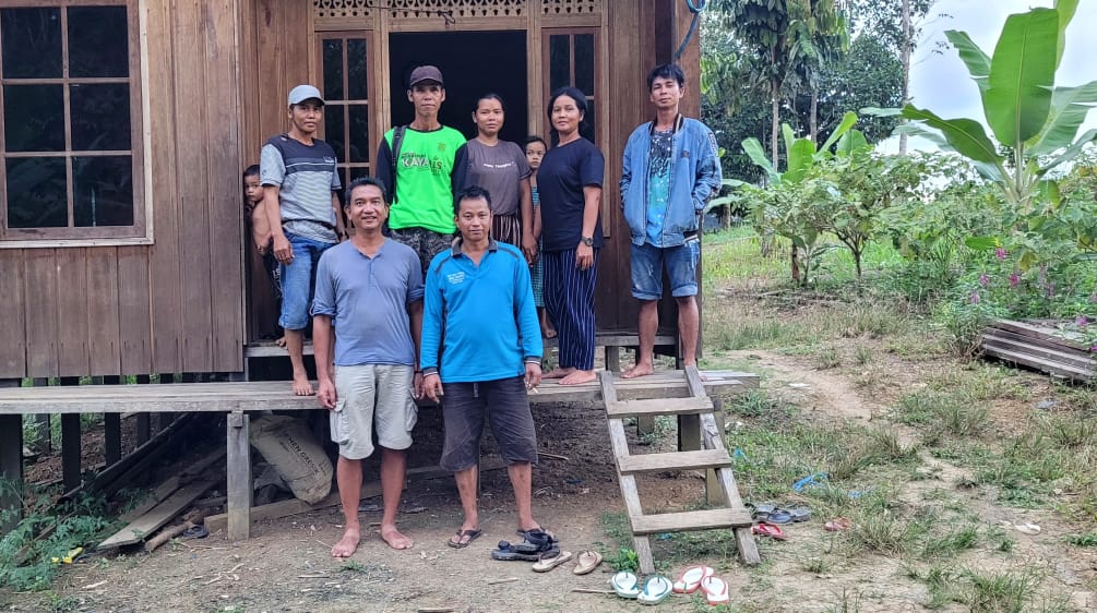 Nueve personas, incluido un representante de Salva la Selva, delante de una casa de madera